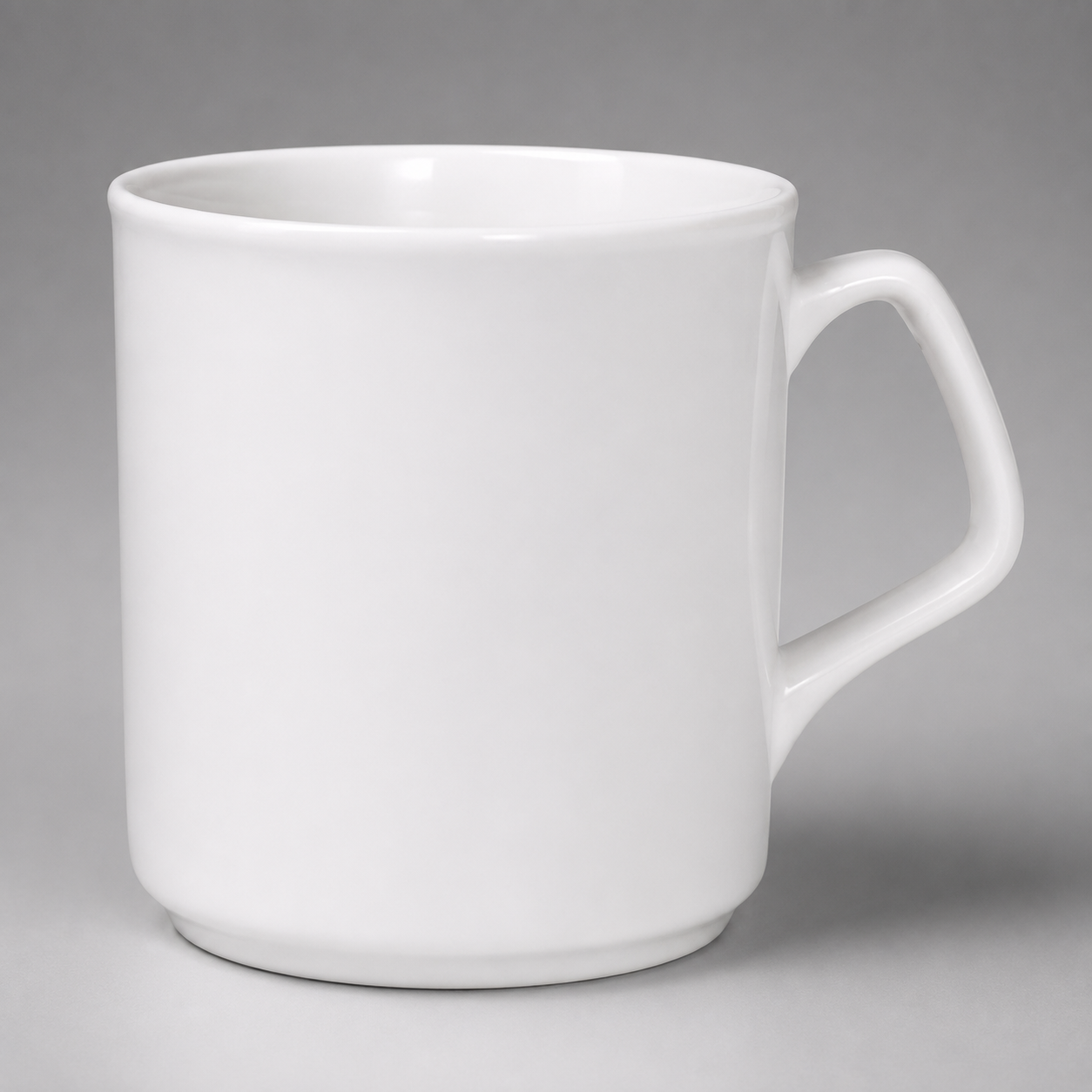 A plain white ceramic mug with a handle on the right side, photographed against a neutral gray background.