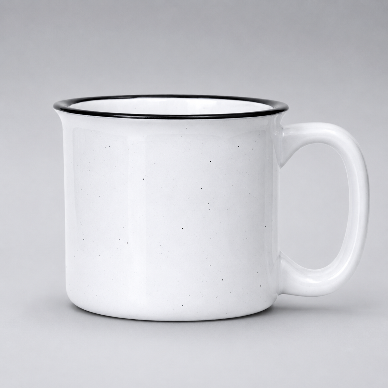 A white ceramic mug with a black rim and a small speckled texture, shown against a neutral gray background.